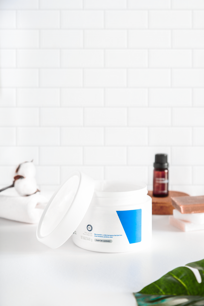 Open cosmetic cream jar on white background with natural decor.